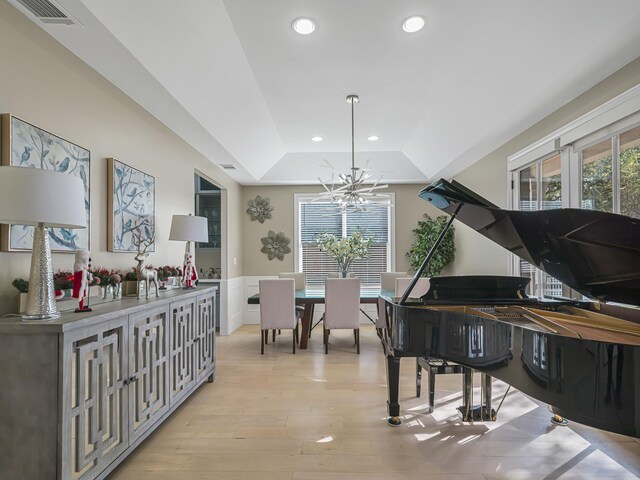 sitting room featuring a raised ceiling, light wood-type flooring, and a notable chandelier