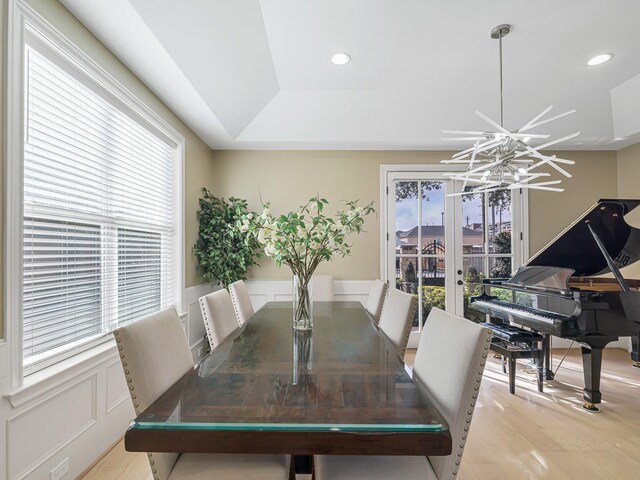 dining area featuring a tray ceiling, light wood-type flooring, and an inviting chandelier