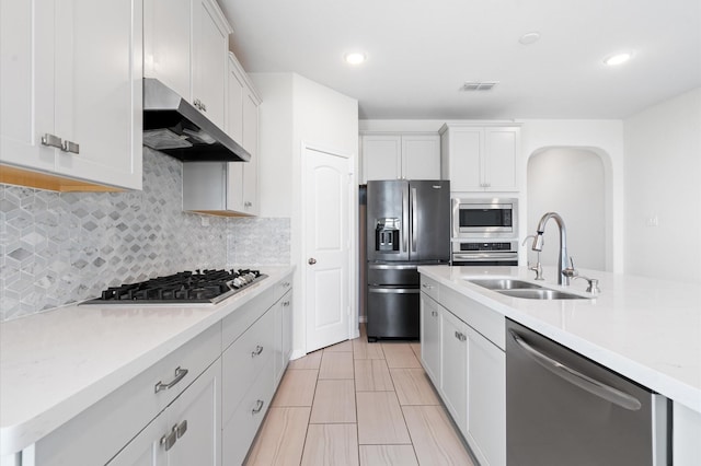 kitchen with tasteful backsplash, sink, white cabinets, and appliances with stainless steel finishes