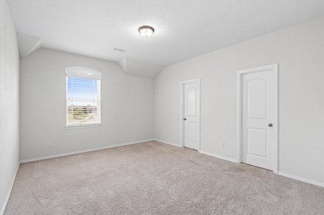 unfurnished room with lofted ceiling and light carpet