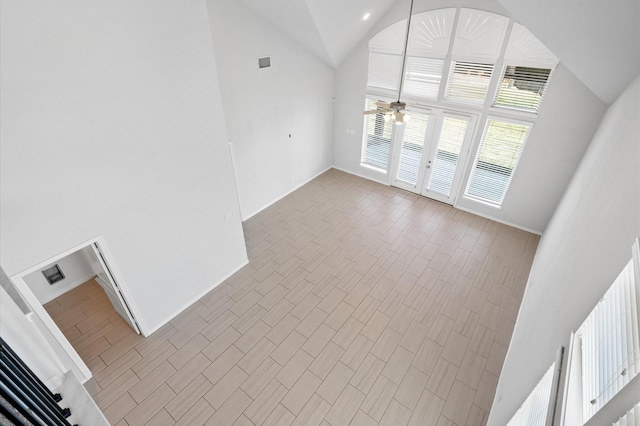 unfurnished living room with ceiling fan and high vaulted ceiling