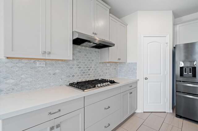 kitchen with decorative backsplash, white cabinetry, stainless steel appliances, and light tile patterned floors