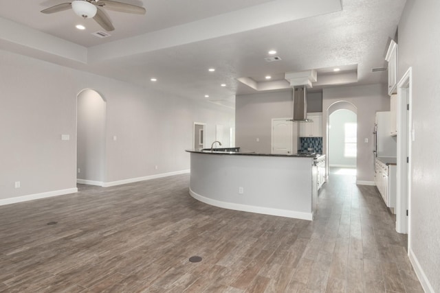 kitchen featuring a tray ceiling, range hood, white cabinets, and dark hardwood / wood-style floors