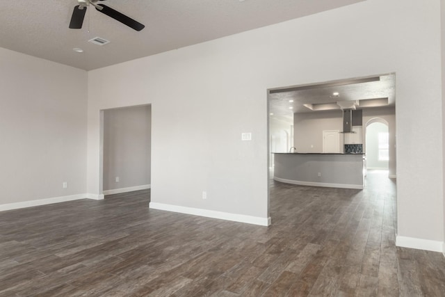 unfurnished living room featuring a textured ceiling, ceiling fan, and dark wood-type flooring