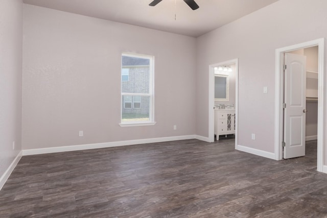 unfurnished bedroom featuring ensuite bath, ceiling fan, a spacious closet, and dark hardwood / wood-style floors