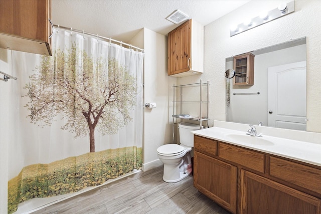 bathroom featuring a textured ceiling, vanity, toilet, and wood-type flooring