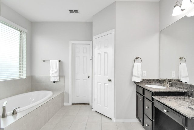 bathroom with tile patterned flooring, vanity, and tiled tub