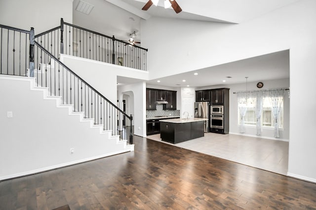 unfurnished living room featuring ceiling fan, sink, high vaulted ceiling, and hardwood / wood-style flooring