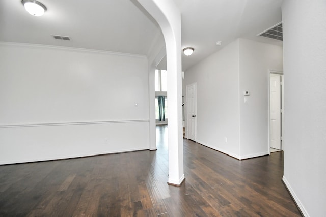 empty room with crown molding and dark wood-type flooring