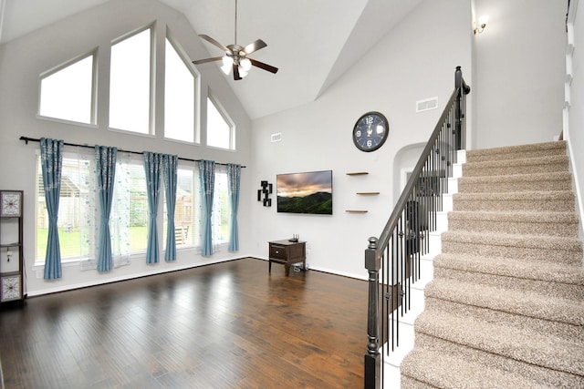 unfurnished living room with high vaulted ceiling, ceiling fan, and dark wood-type flooring