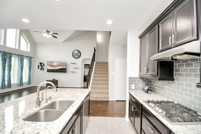 kitchen featuring dark brown cabinetry, light stone countertops, sink, stainless steel appliances, and lofted ceiling