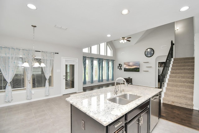 kitchen featuring vaulted ceiling, sink, pendant lighting, light tile patterned floors, and an island with sink