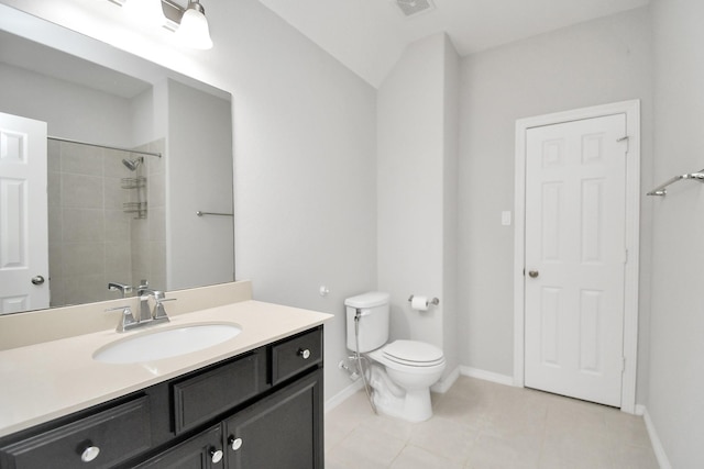 bathroom featuring vanity, lofted ceiling, tile patterned flooring, toilet, and tiled shower