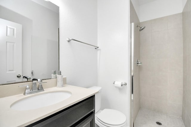 bathroom featuring a tile shower, vanity, and toilet