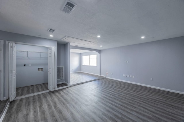 basement featuring a textured ceiling and dark hardwood / wood-style floors