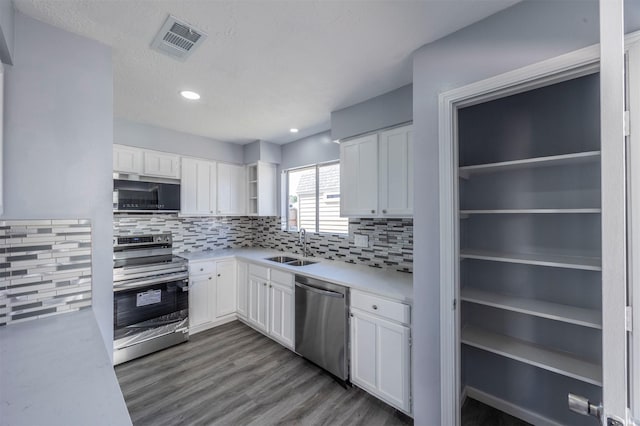 kitchen featuring decorative backsplash, appliances with stainless steel finishes, sink, wood-type flooring, and white cabinetry