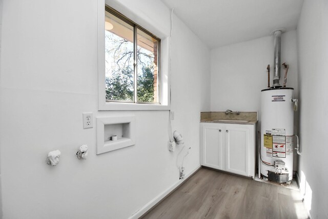 washroom with cabinets, light hardwood / wood-style floors, gas water heater, and sink