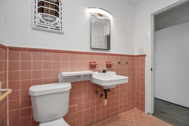 bathroom with toilet and tile walls