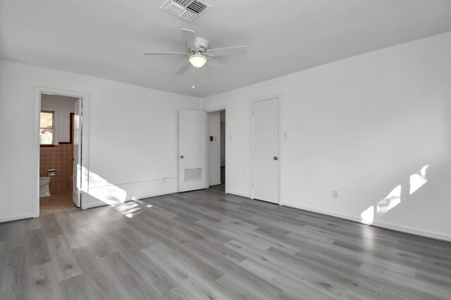 unfurnished bedroom featuring ceiling fan, wood-type flooring, and ensuite bath