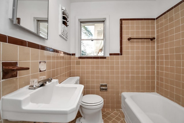 bathroom featuring a bathtub, tile patterned floors, sink, toilet, and tile walls