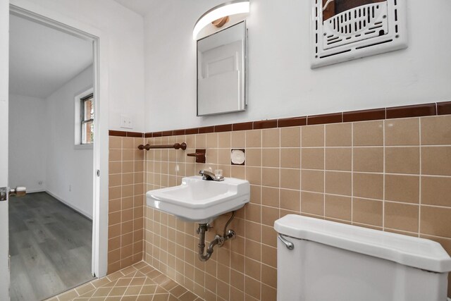 bathroom featuring toilet, tile walls, and sink