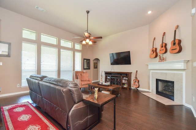 living room featuring ceiling fan, vaulted ceiling, dark wood-type flooring, and a tiled fireplace