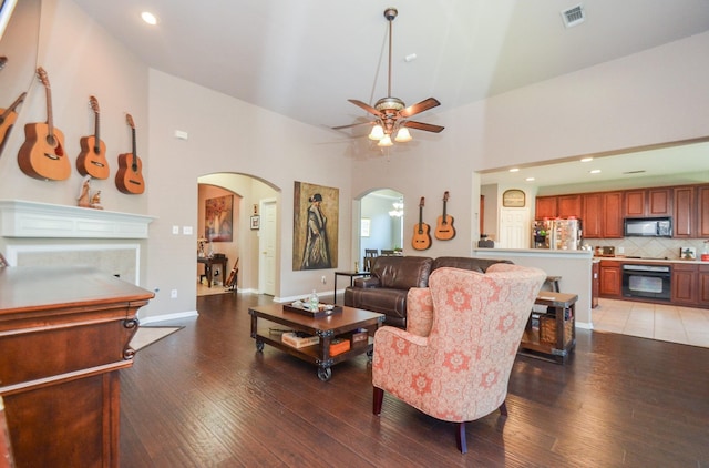 living room with hardwood / wood-style flooring, ceiling fan, and high vaulted ceiling