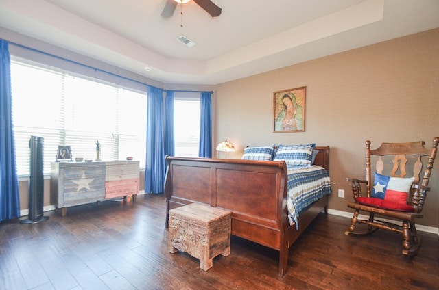 bedroom featuring a raised ceiling, multiple windows, dark wood-type flooring, and ceiling fan