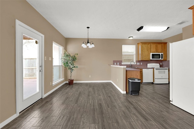 kitchen with kitchen peninsula, dark hardwood / wood-style flooring, decorative light fixtures, plenty of natural light, and white appliances