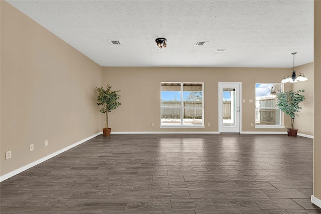 spare room featuring an inviting chandelier, a textured ceiling, and a wealth of natural light