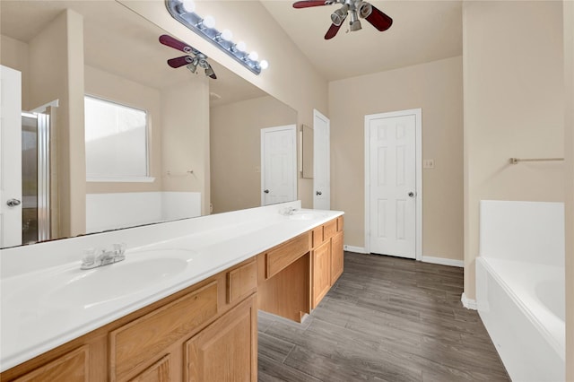 bathroom featuring ceiling fan, a washtub, hardwood / wood-style flooring, and vanity