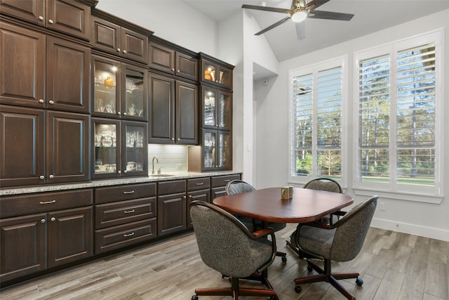 dining space featuring ceiling fan, light hardwood / wood-style floors, sink, and vaulted ceiling