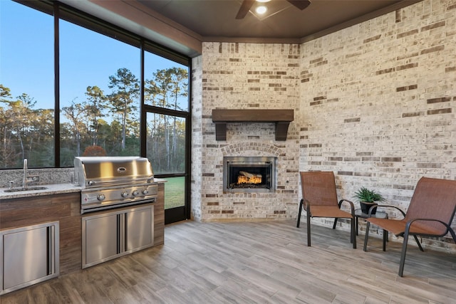 sunroom / solarium featuring ceiling fan, sink, and an outdoor brick fireplace