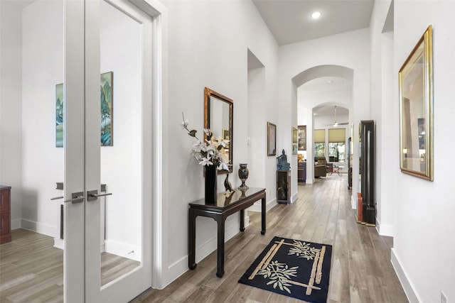 hall featuring hardwood / wood-style floors, a towering ceiling, and french doors