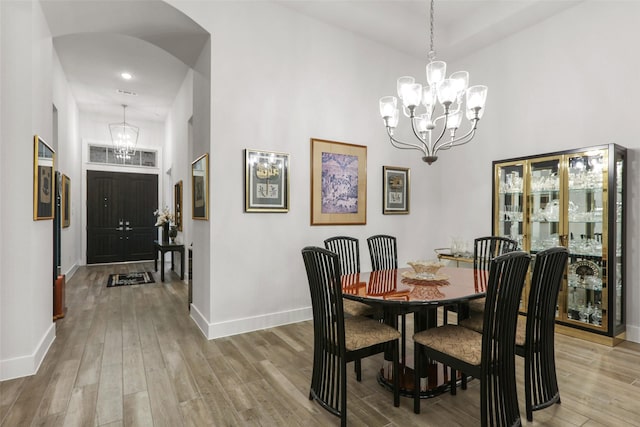 dining space with a high ceiling, light hardwood / wood-style floors, and a notable chandelier