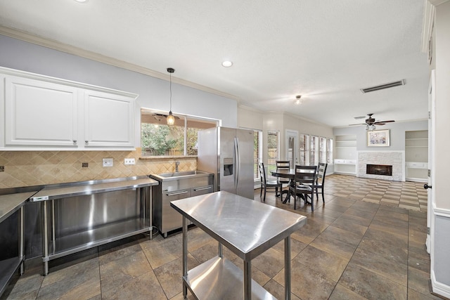 kitchen with stainless steel counters, ceiling fan, stainless steel fridge, pendant lighting, and white cabinets