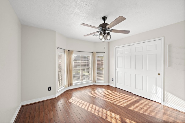 unfurnished bedroom featuring hardwood / wood-style floors, a textured ceiling, a closet, and ceiling fan