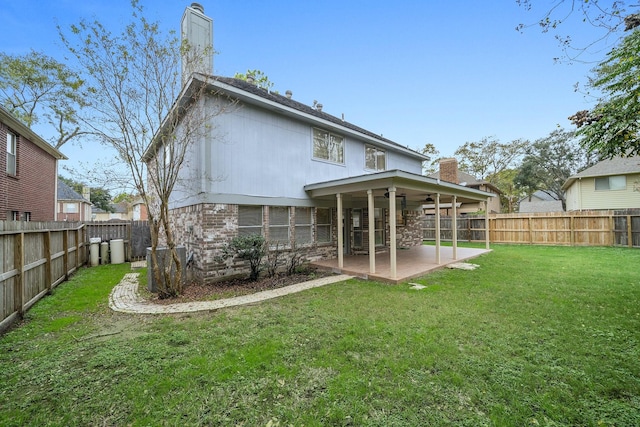 rear view of property with ceiling fan, a patio area, and a lawn