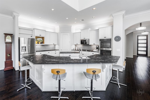 kitchen with a kitchen bar, white cabinets, dark wood-type flooring, and appliances with stainless steel finishes