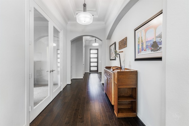 corridor with crown molding, a raised ceiling, and dark wood-type flooring