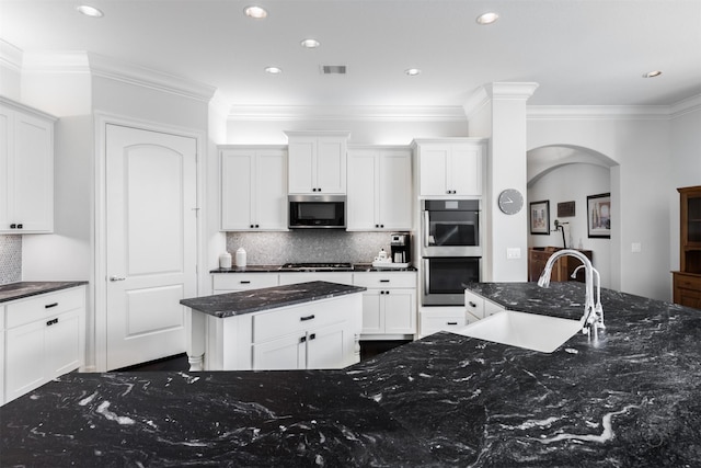 kitchen featuring white cabinets, sink, stainless steel appliances, and dark stone counters