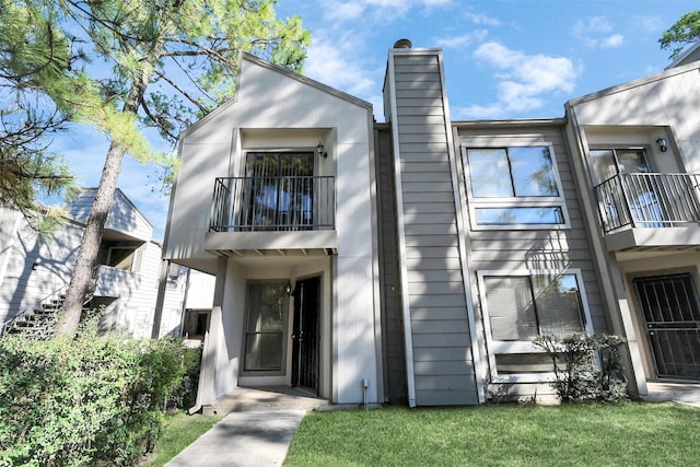 view of front of property featuring a balcony and a front yard