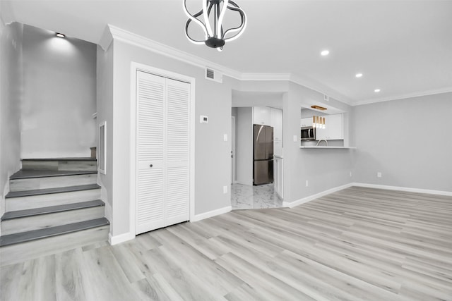 unfurnished living room with a notable chandelier, light wood-type flooring, and crown molding