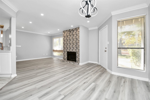 unfurnished living room with a fireplace, plenty of natural light, light hardwood / wood-style flooring, and ornamental molding