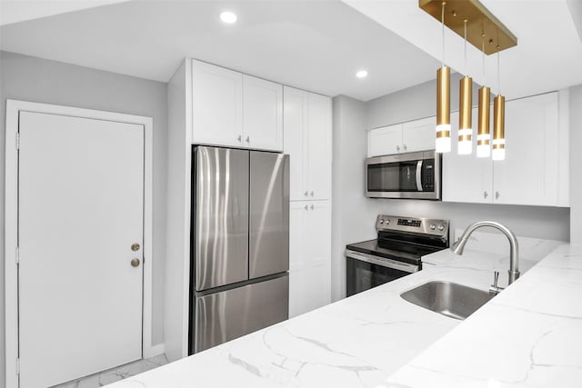 kitchen featuring white cabinetry, sink, hanging light fixtures, stainless steel appliances, and light stone counters