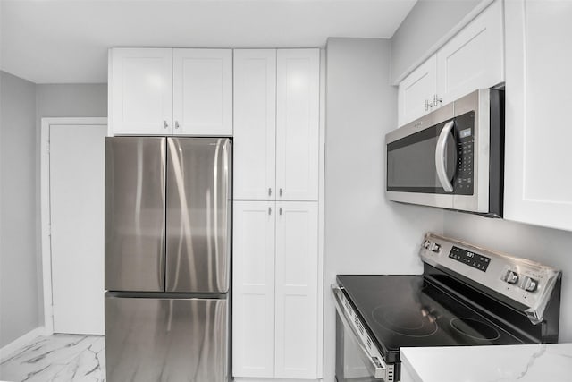 kitchen with light stone countertops, white cabinetry, and appliances with stainless steel finishes