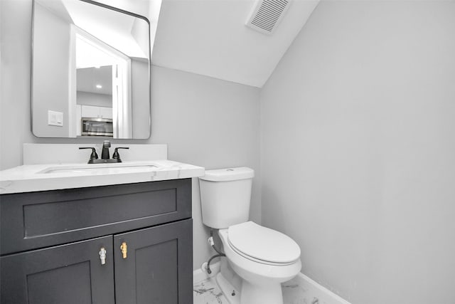 bathroom with vanity, toilet, and lofted ceiling