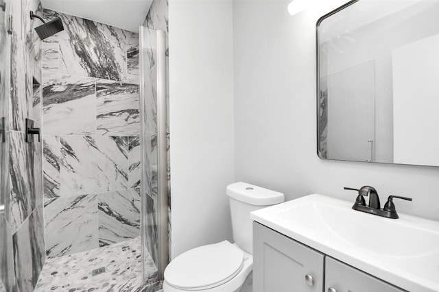 bathroom with vanity, toilet, and tiled shower