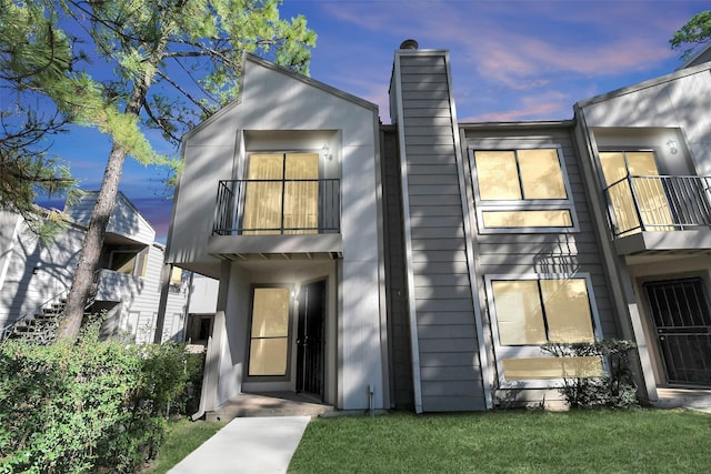 view of front of house featuring a lawn and a balcony