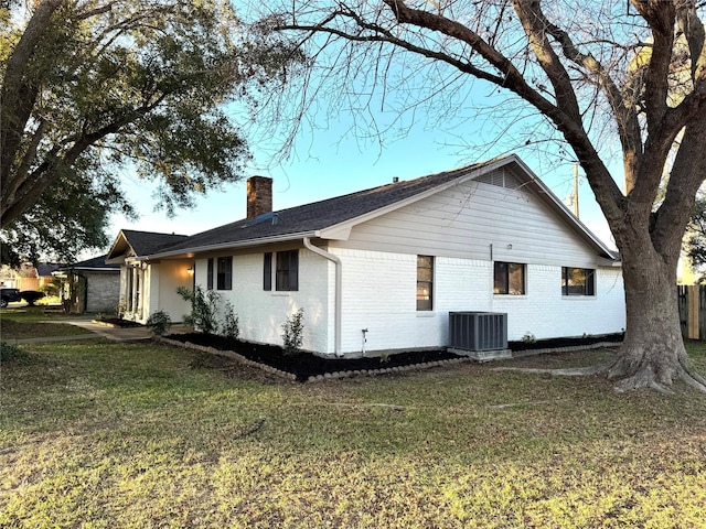 view of side of property featuring a yard and central AC